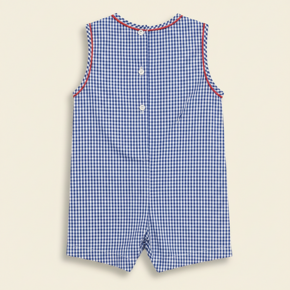Petit Ami navy gingham shortall, back, showing the buttoned shoulder and back closure with red piping