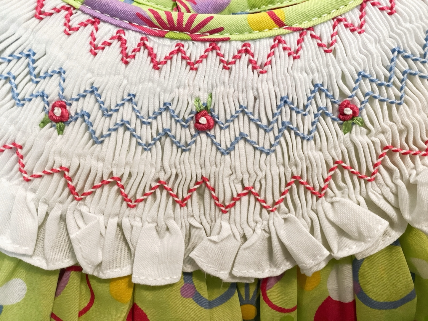 Detail of the hand-smocked collar with pink and blue zigzag rows and embroidered rosebuds
