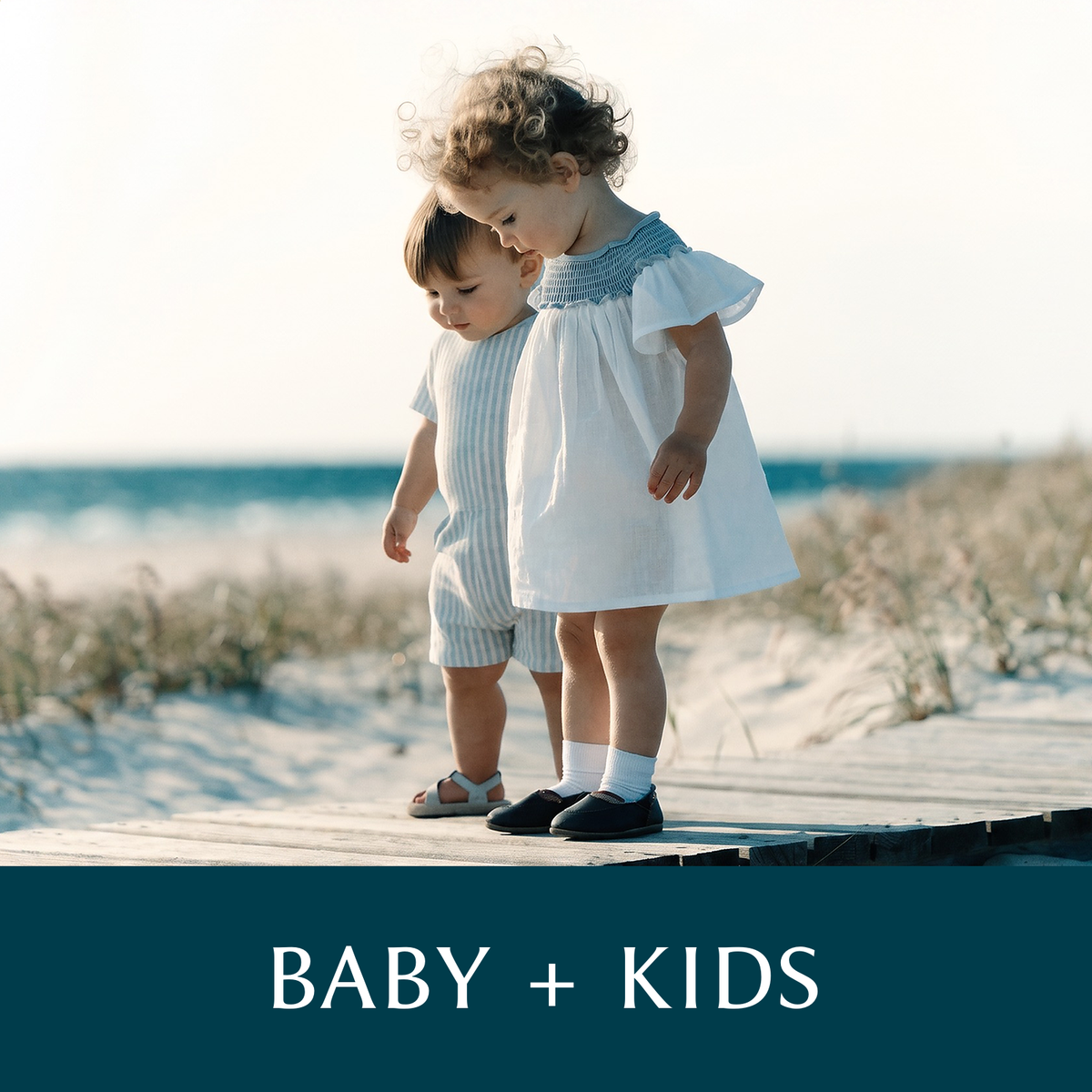 Two toddlers on a beach boardwalk in a striped shortall and white dress, captioned BABY + KIDS