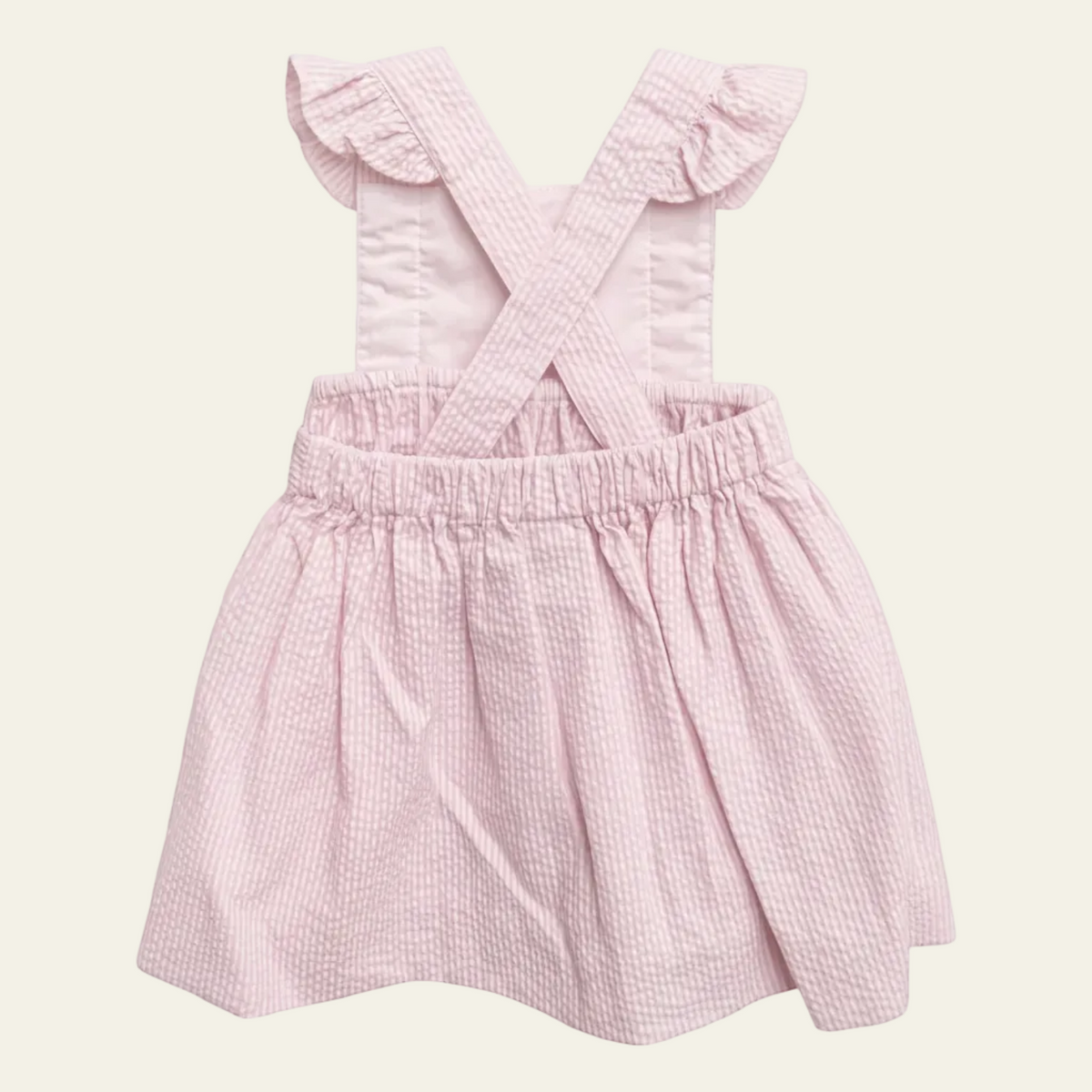Petit Ami pink seersucker pinafore, back, showing the crossed straps and elasticated waist