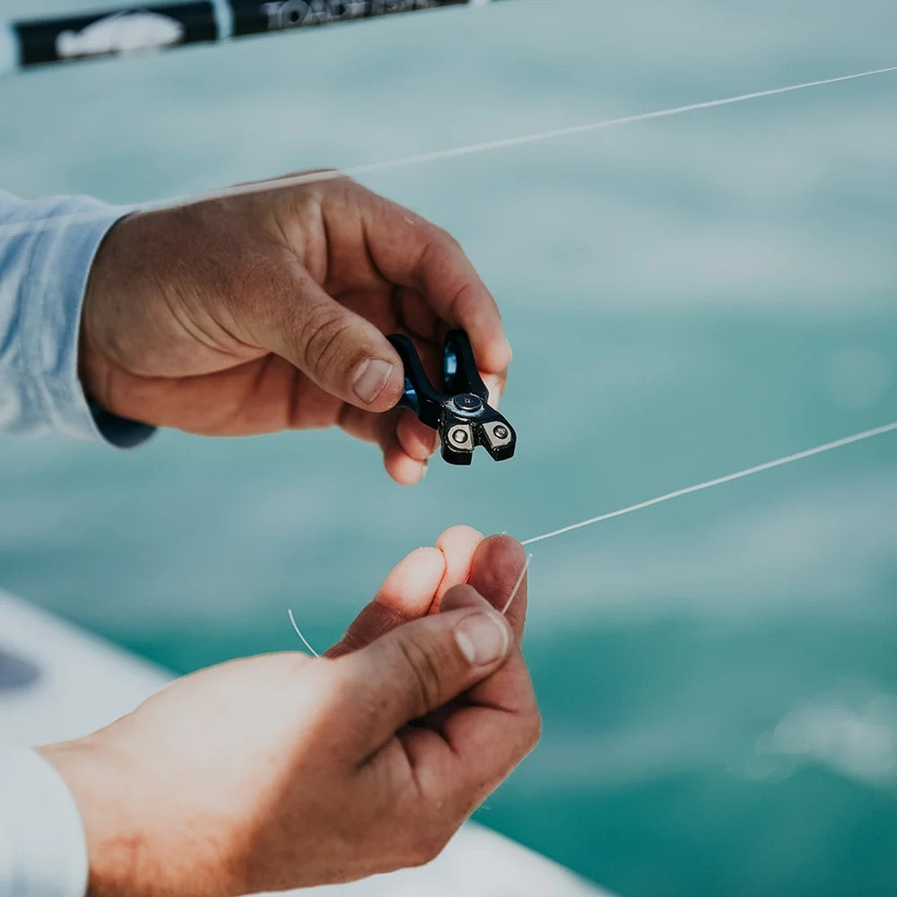 Angler cutting fishing line with Toadfish nippers on a boat over green Gulf water