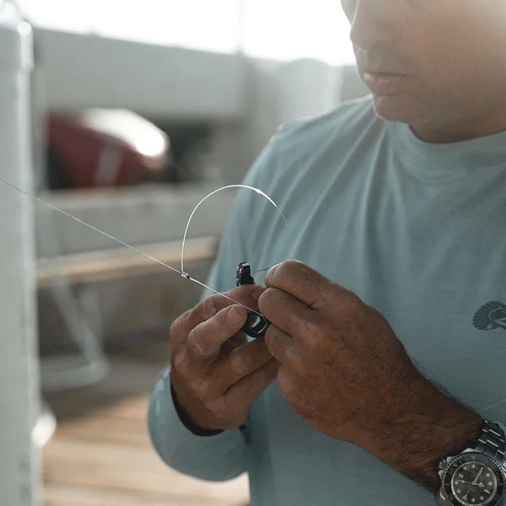 Angler on a dock trimming line with Toadfish nippers tethered to his shirt on the retractable clip