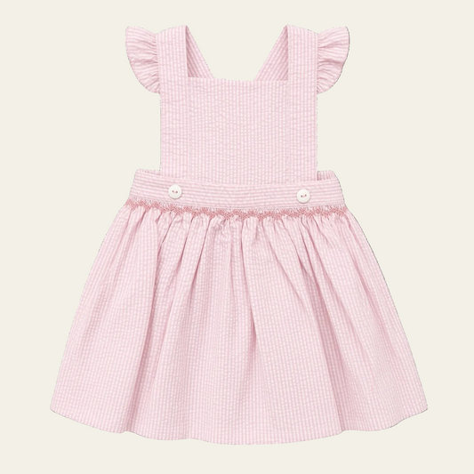 Petit Ami pink seersucker pinafore with hand-smocked waist and flutter sleeves, front