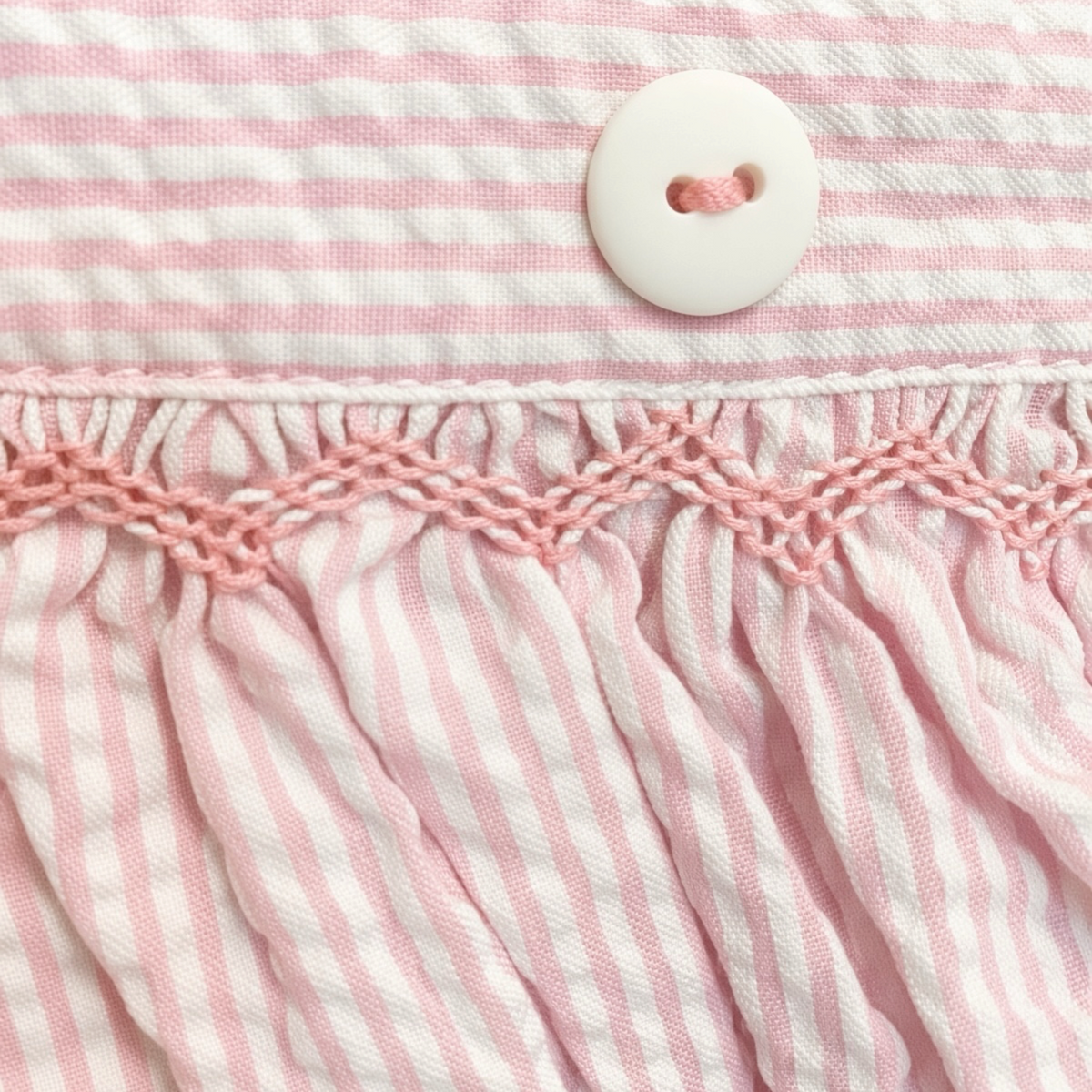 Detail of the pink hand-smocking and scalloped edge at the pinafore waistband