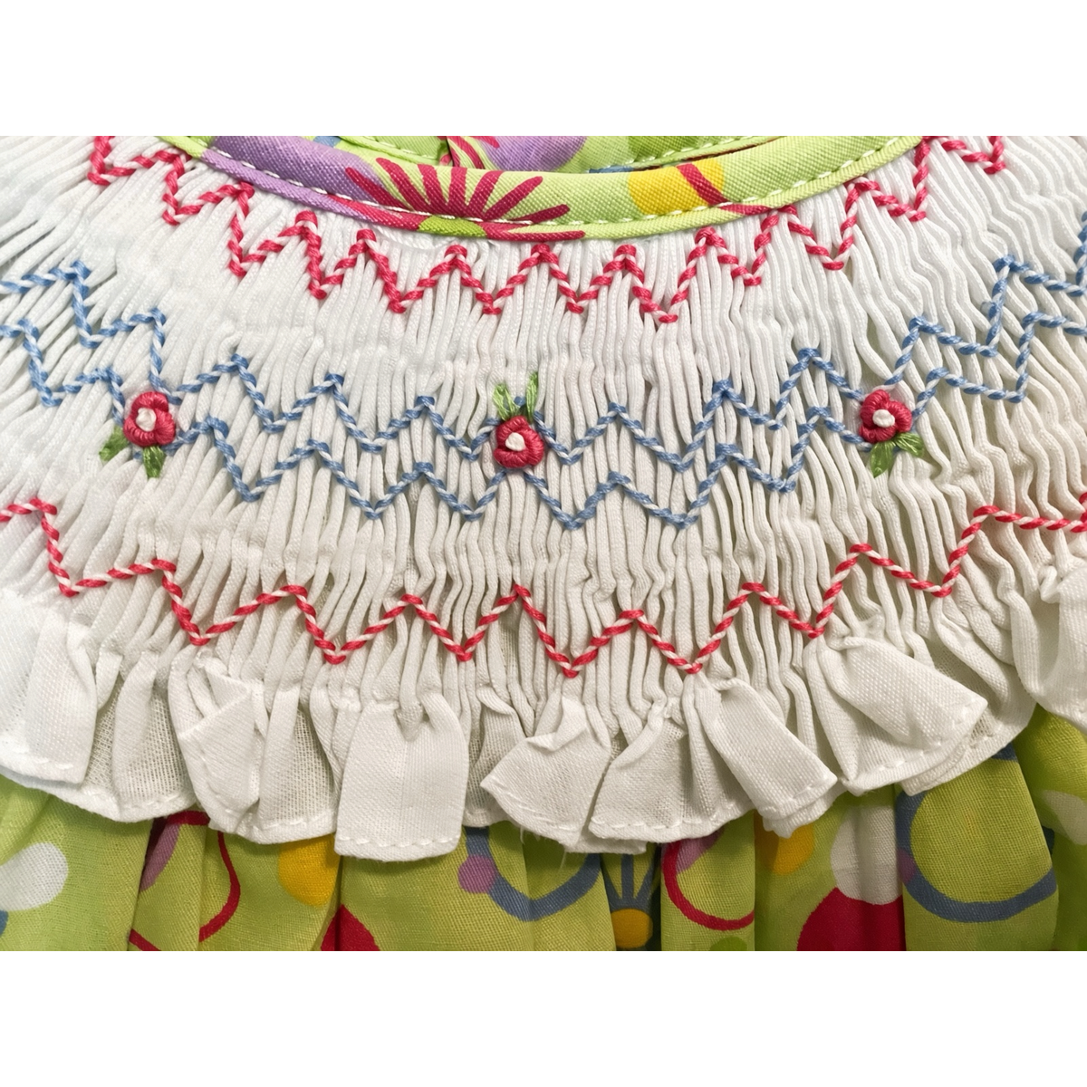 Detail of the hand-smocked collar with pink and blue zigzag rows and embroidered rosebuds